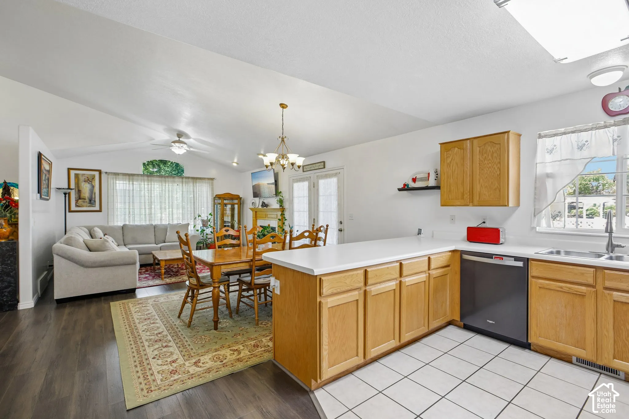 Open concept living area featuring a kitchen with light wood cabinetry, a white countertop, and white tile flooring