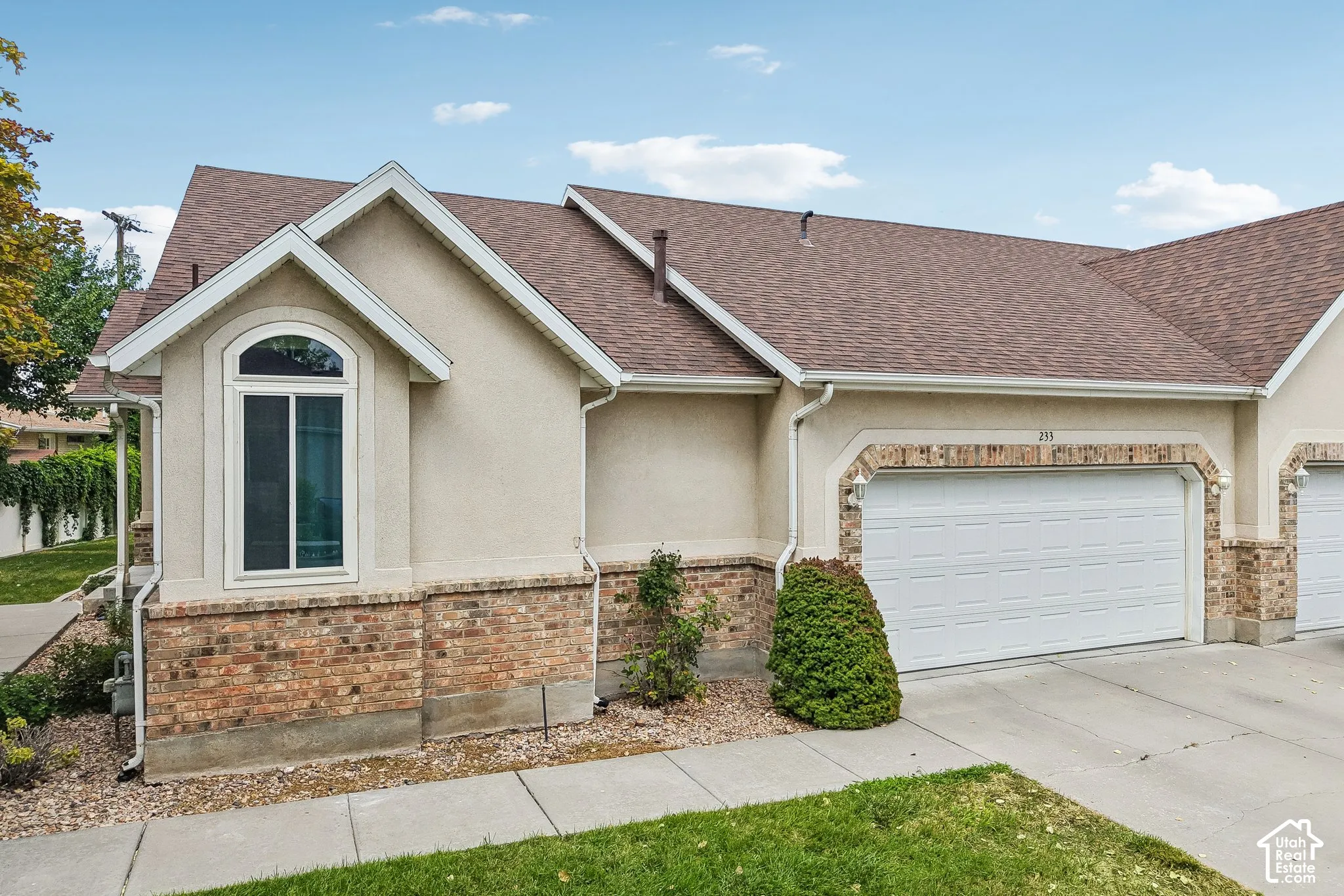 Exterior featuring a brick and stucco facade, an arched window, and an attached garage with a white door
