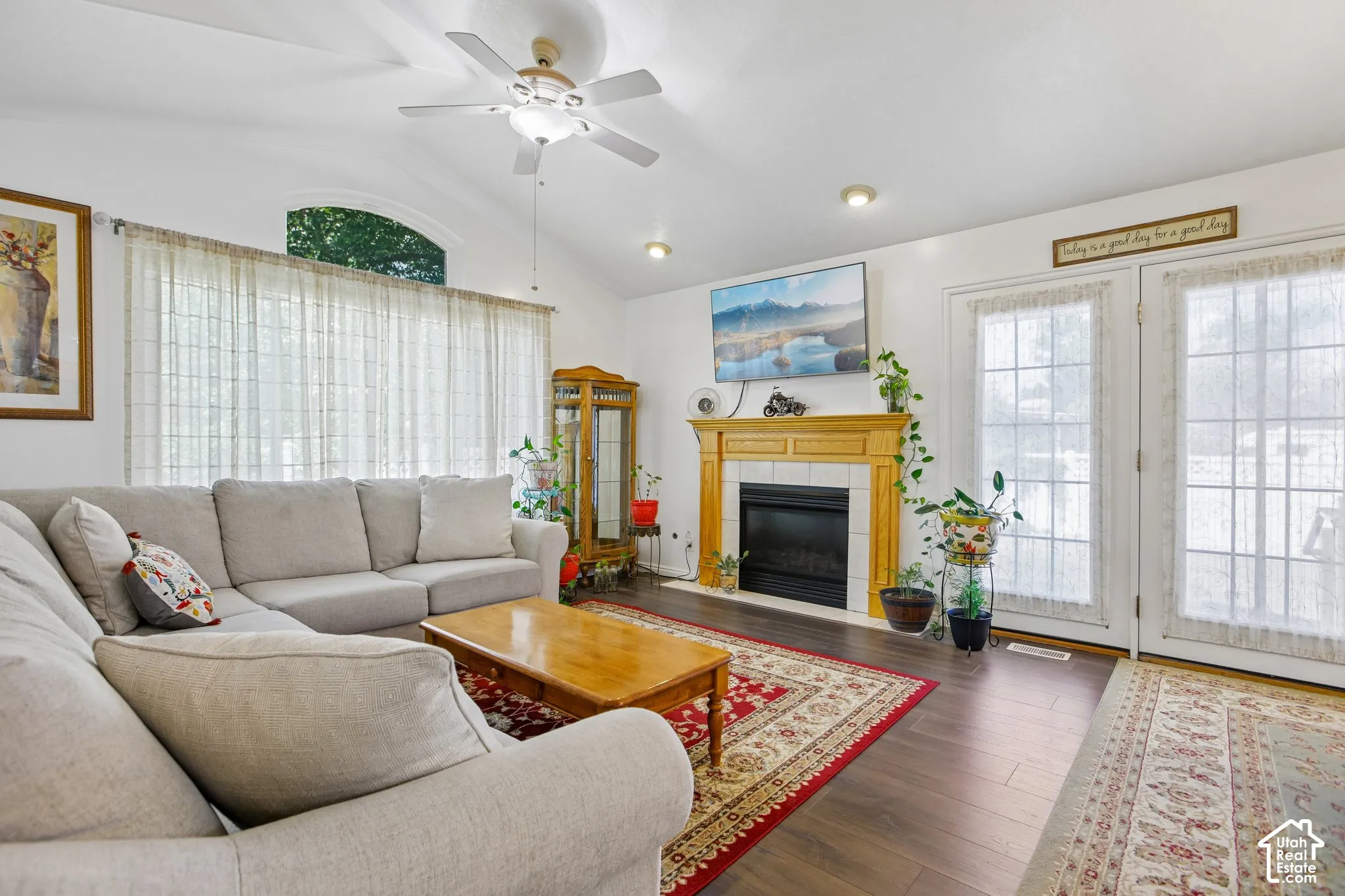 Spacious living area featuring vaulted ceilings, wood-finish flooring, and a fireplace with a wood mantle and tile surround