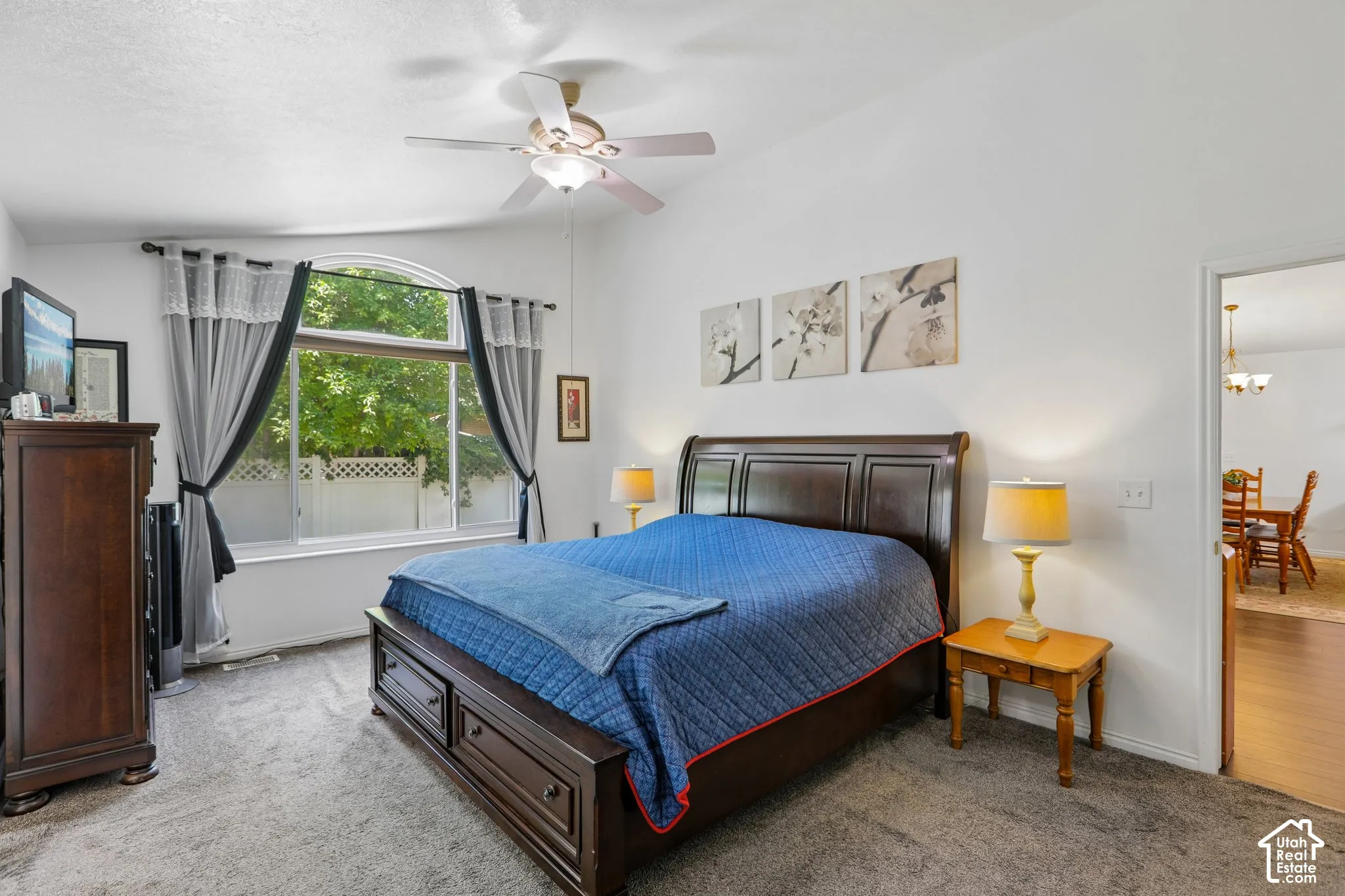 Carpeted room featuring a large arched window, vaulted ceiling, and ceiling fan