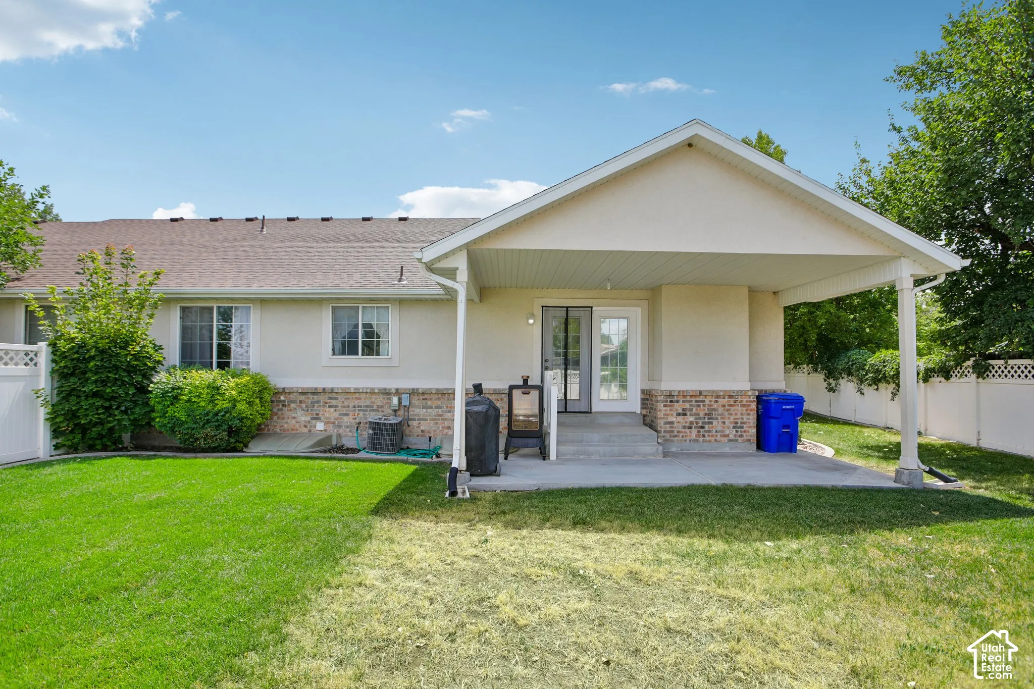 Expansive backyard featuring a covered patio, concrete steps, and a sliding glass door entry