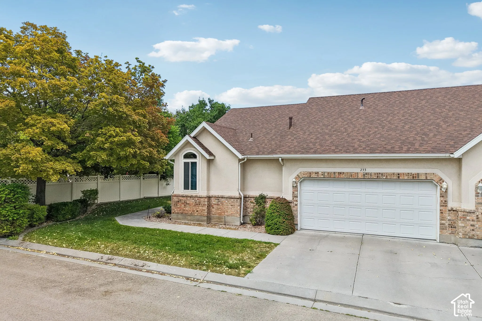 Stucco exterior with brick detailing, an arched window, and a white paneled garage door