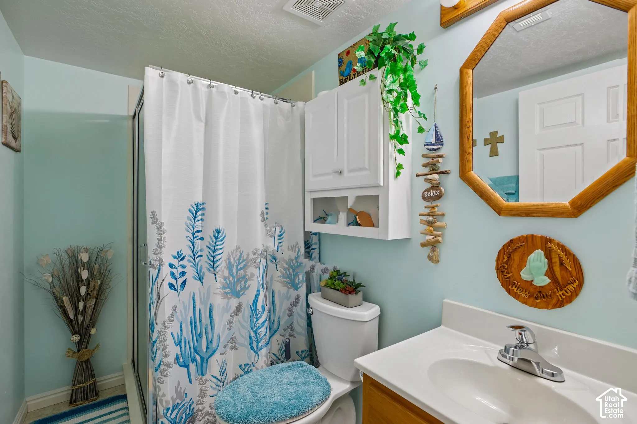 Bathroom featuring a shower enclosure, white shower curtain with blue botanical pattern, and light blue wall color
