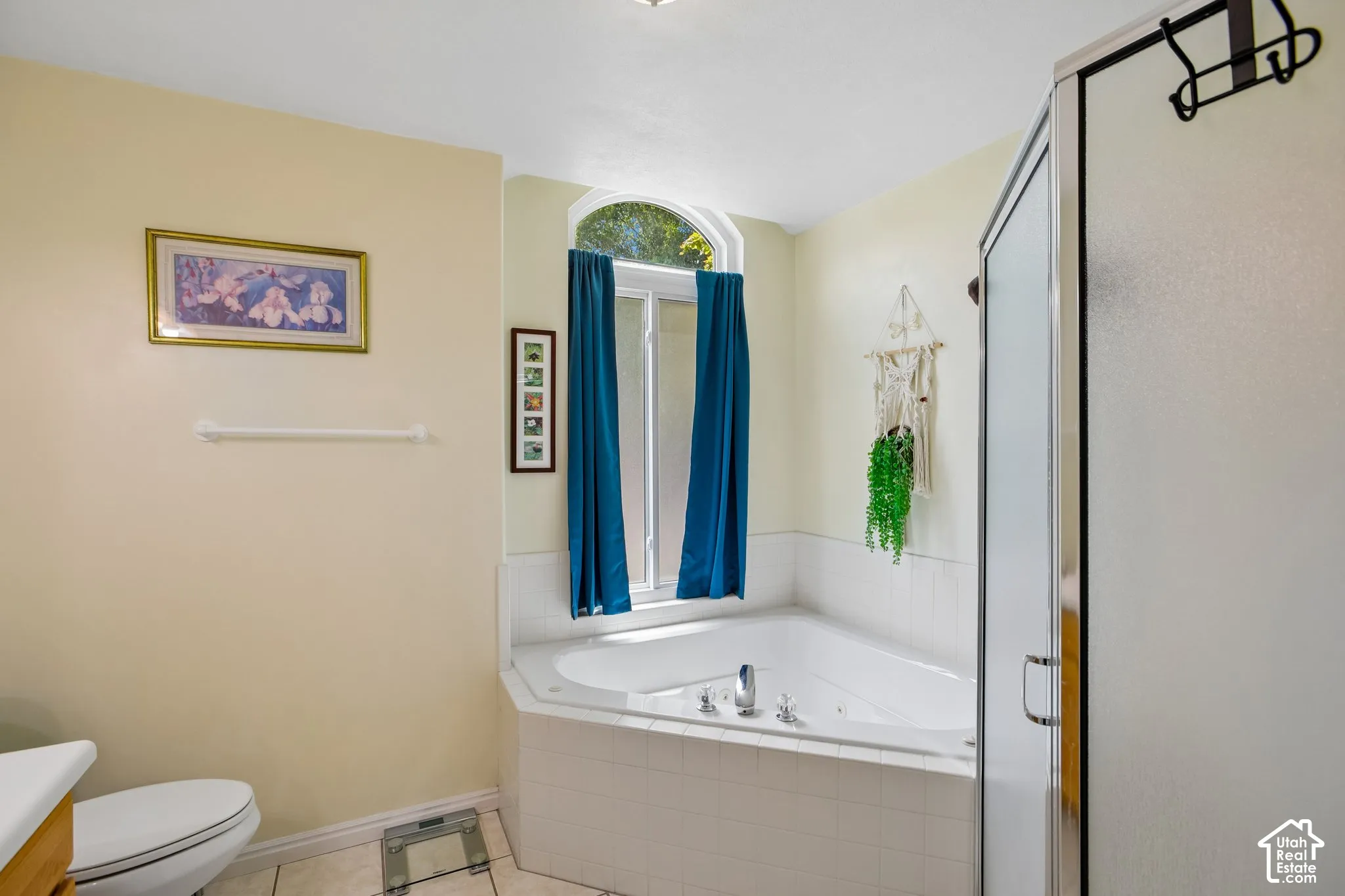 Jetted corner tub with tile surround, framed by an arched window