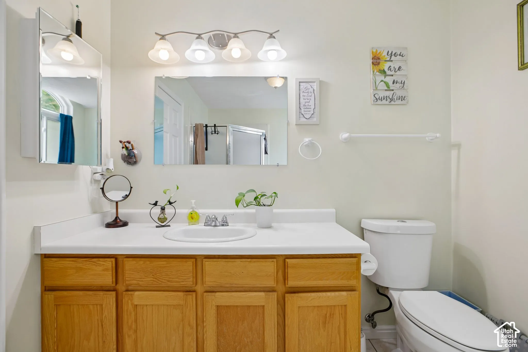 Bathroom vanity with light wood-finish cabinetry, white countertop, and integrated sink