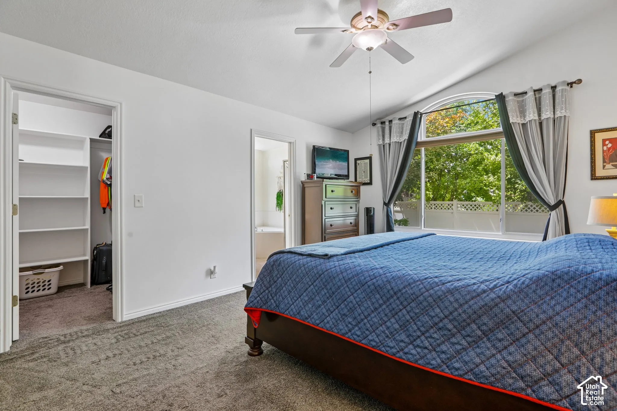 Carpeted bedroom featuring a vaulted ceiling and a ceiling fan with integrated lighting