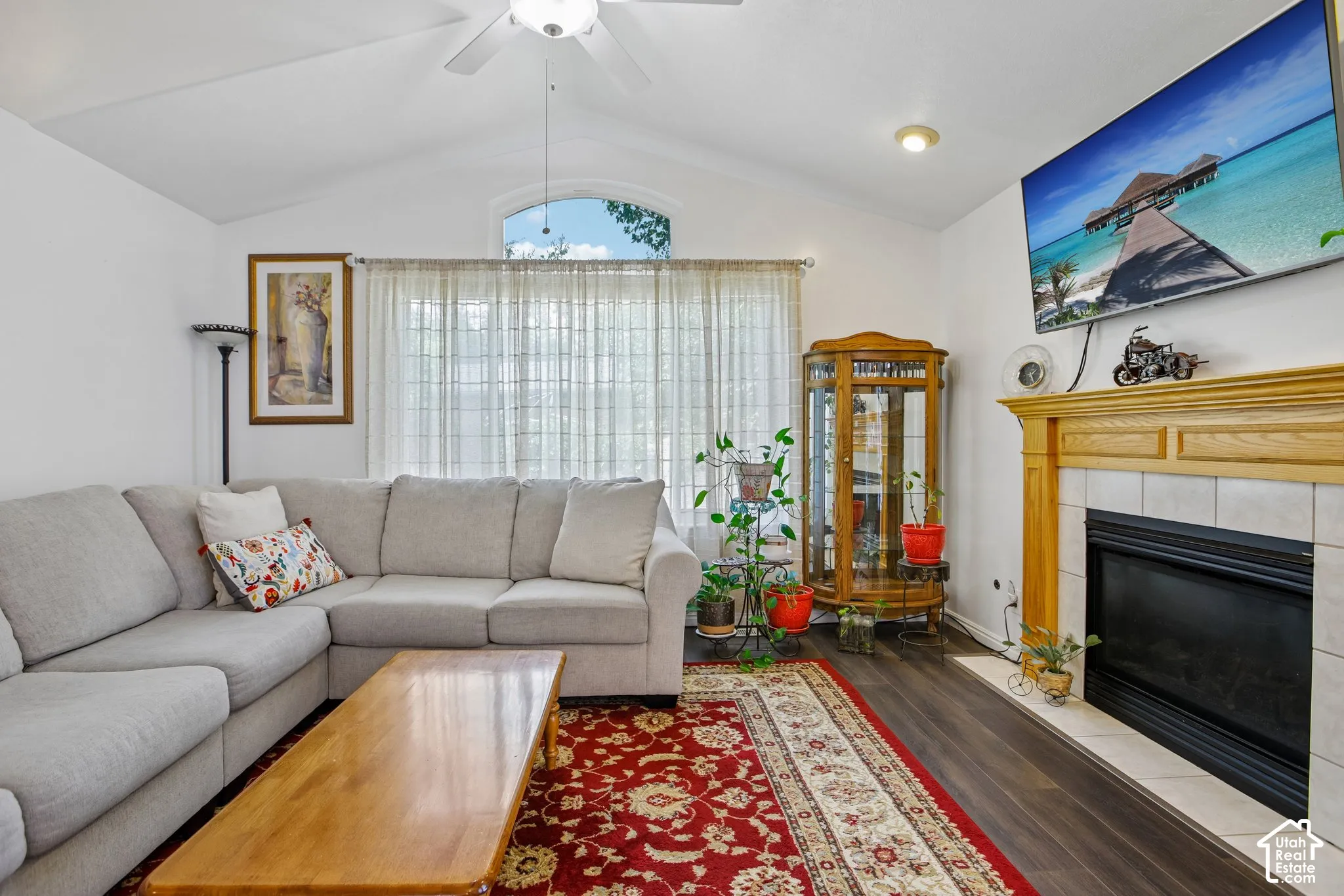 Vaulted ceiling living area featuring wood-finish flooring, a contemporary ceiling fan, and an arched window