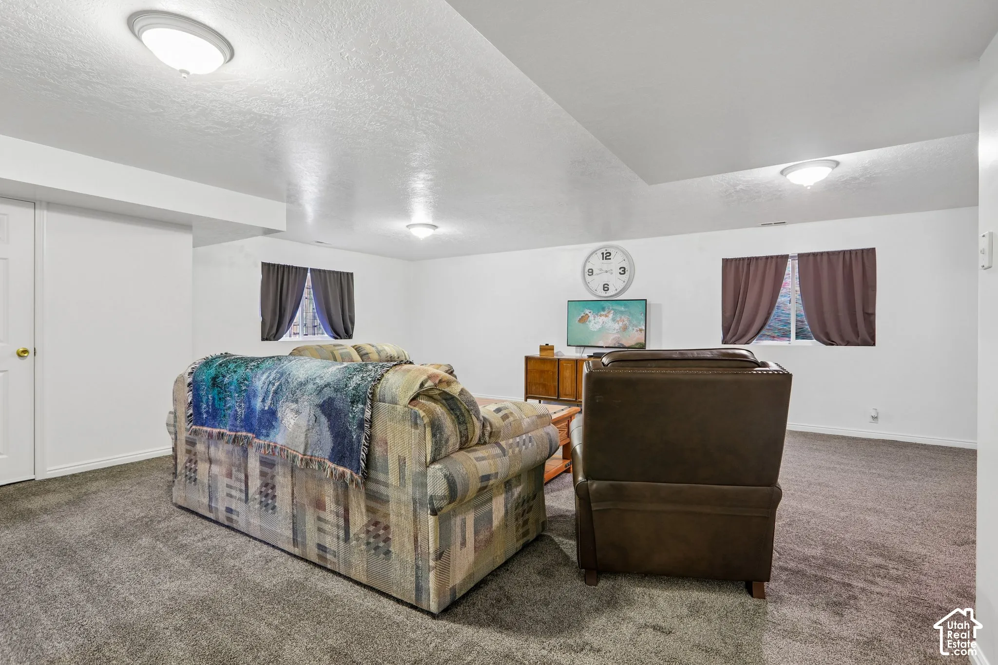 Spacious room featuring gray carpeting, white painted walls, and ceiling-mounted lighting fixtures