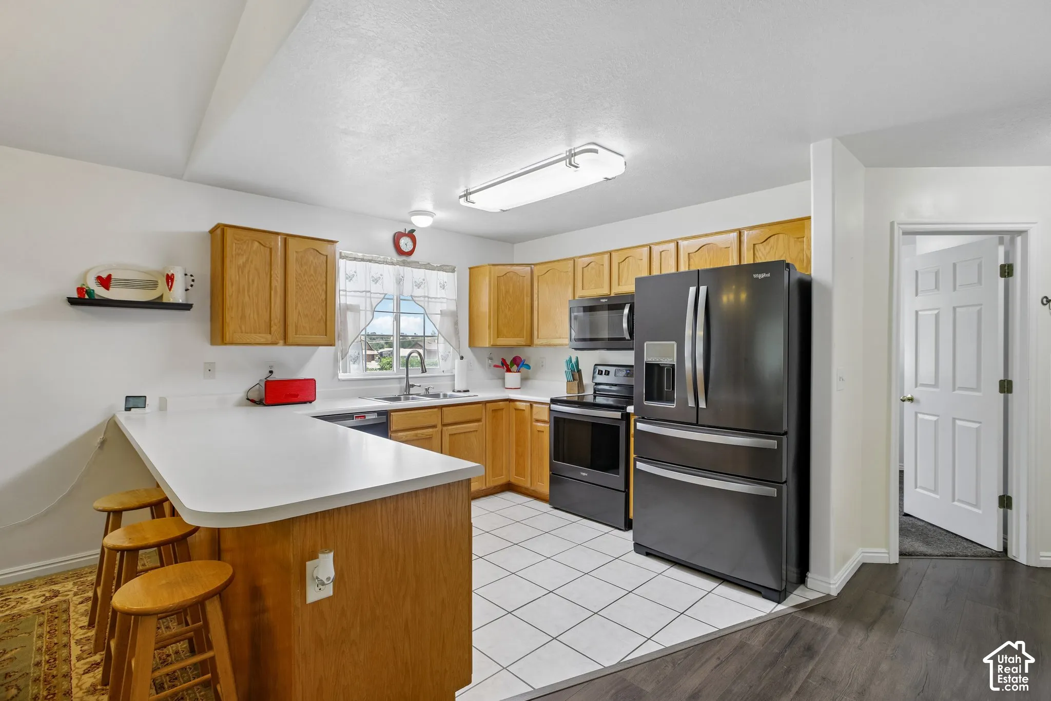 Kitchen featuring light wood cabinetry, white countertops, and black appliances
