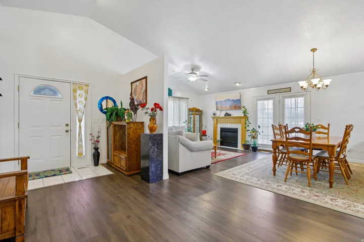 Open-concept living area featuring wood-finish flooring, vaulted ceilings, and a fireplace with a wood mantle