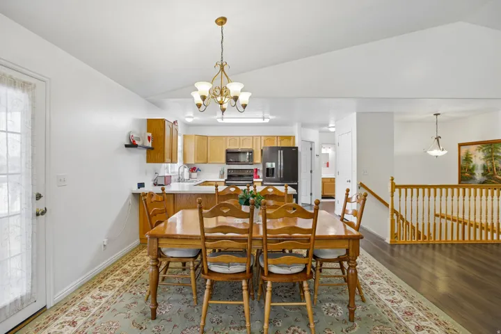Open-concept dining area featuring a vaulted ceiling and an ornate chandelier