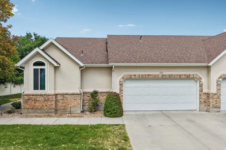 Exterior facade featuring stucco and brick finishes, an arched window, and an attached two-car garage with a panel door