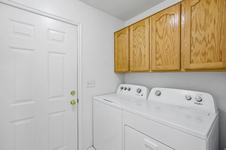 Laundry area featuring a paneled white door, overhead wood cabinetry, and light-colored walls