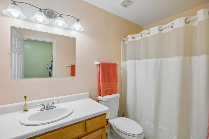 Bathroom featuring a vanity with a wood-finish base and white countertop, an oval undermount sink with a chrome faucet, and a wall-mounted mirror