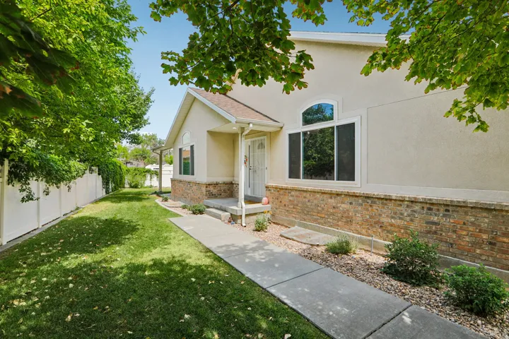 Stucco and brick exterior featuring a covered entry, arched window, and concrete walkway