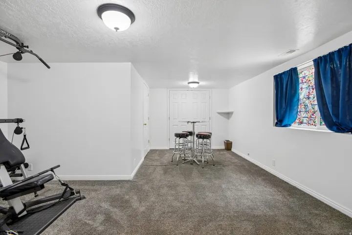 Carpeted room featuring white walls, white baseboards, a window with a white frame, and a flush mount ceiling light fixture