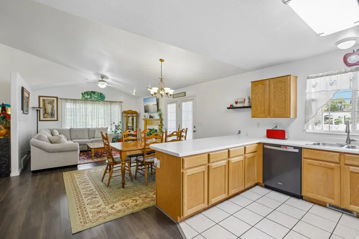 Open concept living area featuring a kitchen with light wood cabinetry, a white countertop, and white tile flooring