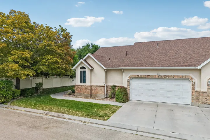 Stucco exterior with brick detailing, an arched window, and a white paneled garage door