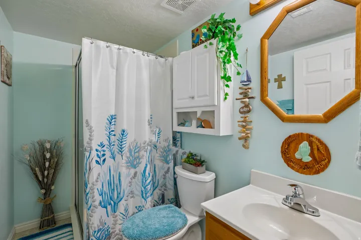 Bathroom featuring a shower enclosure, white shower curtain with blue botanical pattern, and light blue wall color