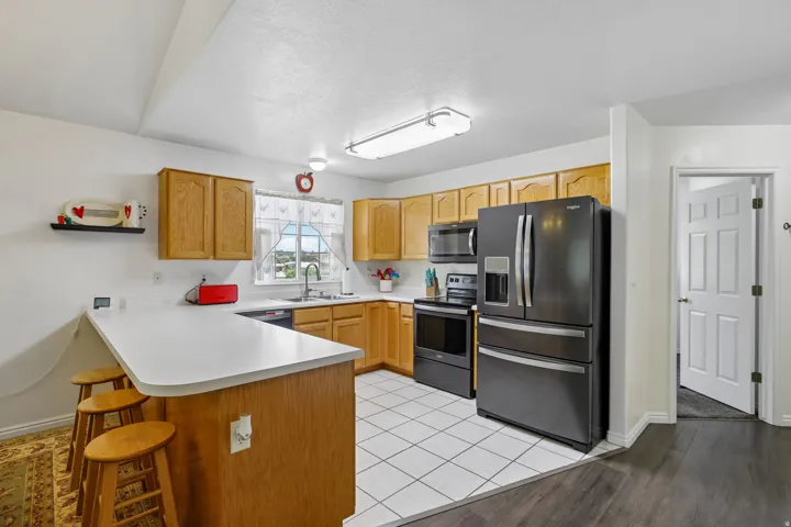 Kitchen featuring light wood cabinetry, white countertops, and black appliances