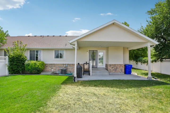 Expansive backyard featuring a covered patio, concrete steps, and a sliding glass door entry