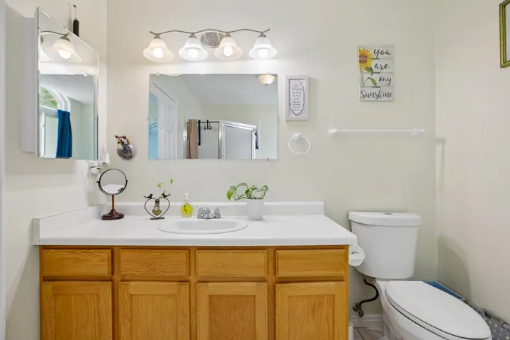 Bathroom vanity with light wood-finish cabinetry, white countertop, and integrated sink