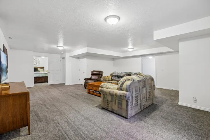 Spacious recreation room featuring neutral carpeting, recessed ceiling lighting, and white baseboards