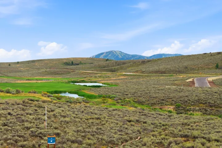 Expansive landscape with a golf course green, two ponds, and mountainous terrain