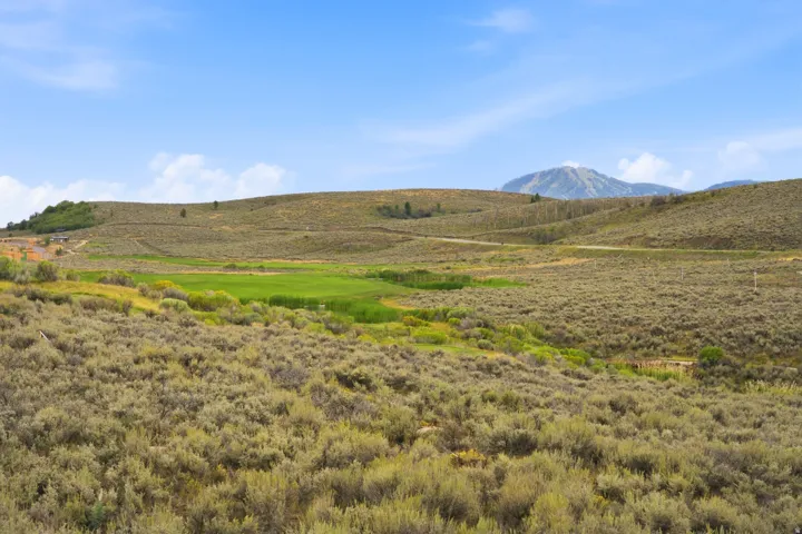 Expansive natural landscape with rolling hills, distant mountains, and varied vegetation