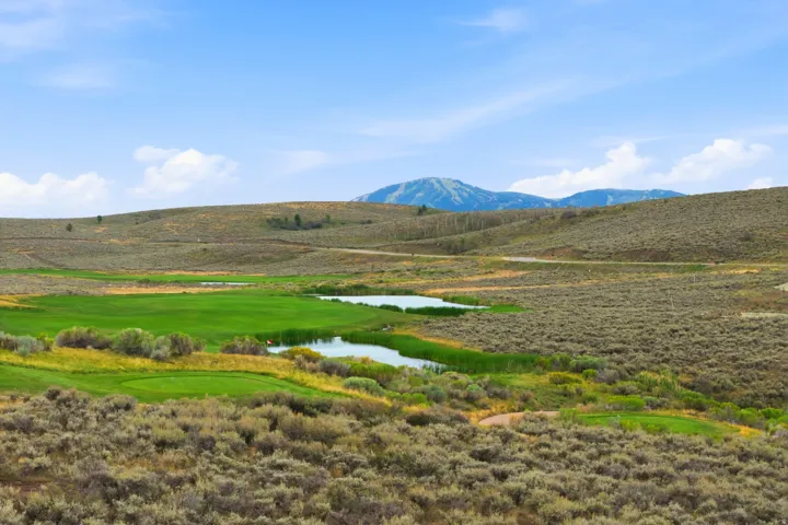 Expansive golf course featuring green fairways, water features, and distant mountains