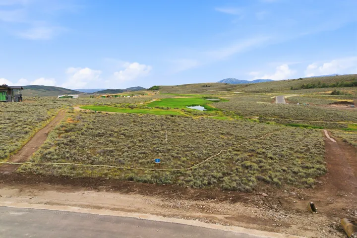 Expansive undeveloped terrain with a visible road, distant water feature, and natural shrubbery