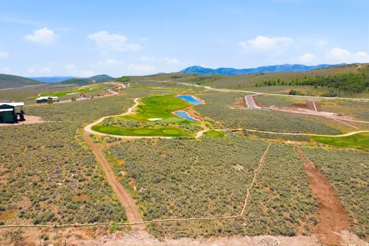 Expansive property with a golf course, multiple water features, and distant mountain scenery