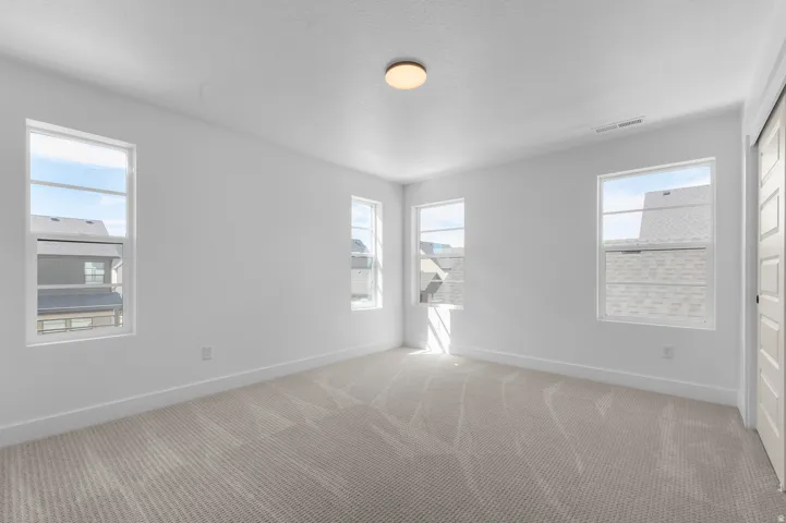Neutral wall color with textured carpet flooring, complemented by multiple windows and a flush mount ceiling fixture