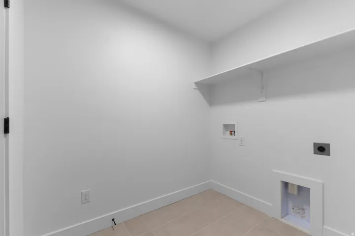 White walls, tile flooring, built-in shelving, and utility hookups