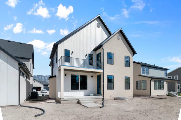 Contemporary exterior with contrasting siding textures, black-framed windows, and a second-story balcony with metal railings