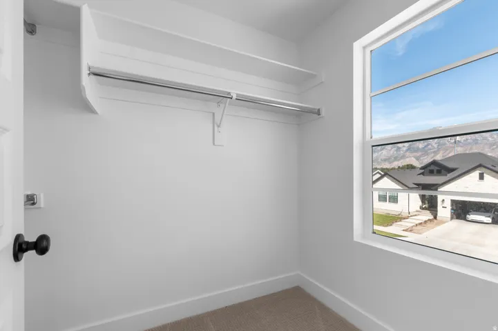 Built-in shelving and hanging rod with a window providing natural light and mountain scenery