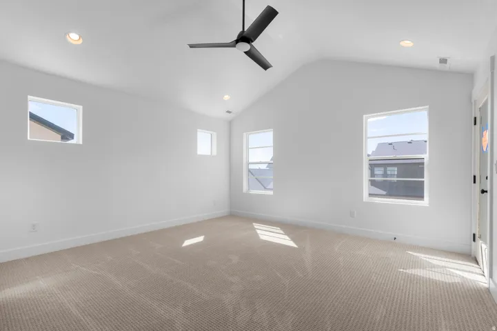 Vaulted ceiling with recessed lighting and a ceiling fan, multiple windows, and neutral carpeting