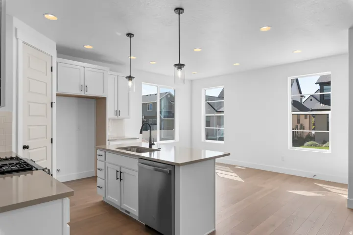Modern kitchen featuring white cabinetry, light-toned countertops, stainless steel appliances, and wood-finish flooring