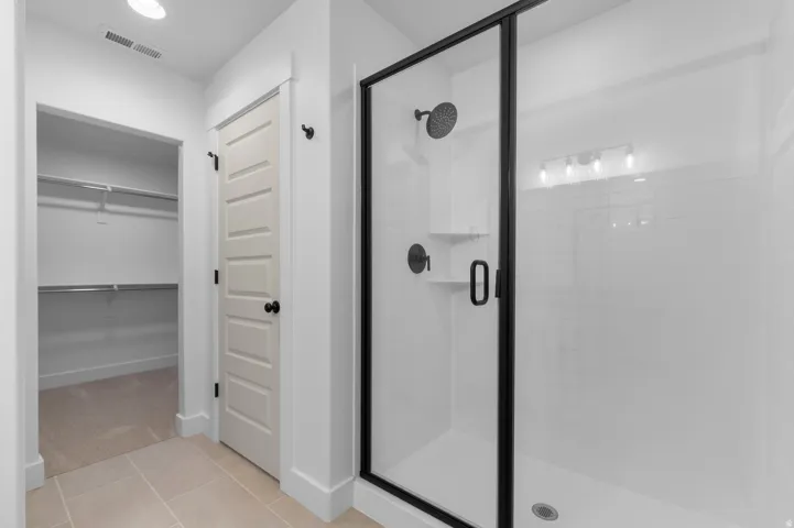 Spacious shower with a black-framed glass enclosure, matte black fixtures, and integrated shelving