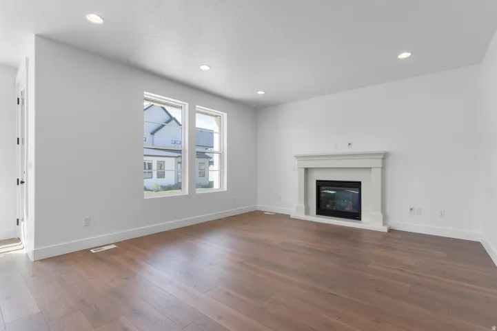 Wood-finish flooring, recessed lighting, dual windows, and a built-in fireplace with mantel