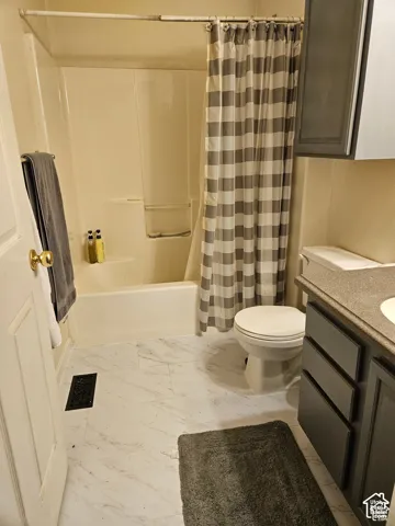 main Bathroom featuring a white tub/shower combination, white toilet, dark gray vanity with a light gray countertop, and light-toned flooring