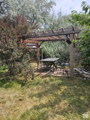 Wood pergola structure over a brick paver patio, surrounded by mature trees and shrubs