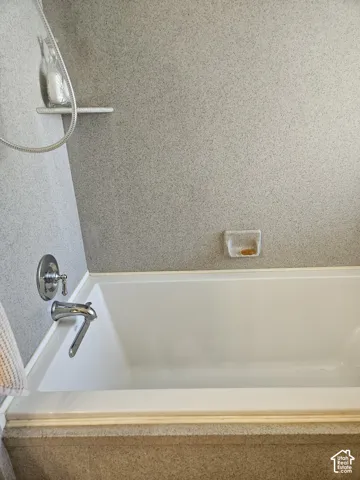 master bath soaking tub White bathtub with chrome fixtures and a built-in soap dish
