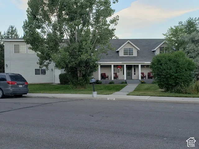Exterior featuring a covered porch with white columns, a dormer window, and a light-colored siding facade