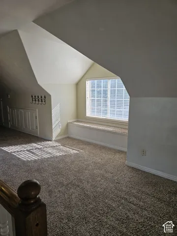 Carpeted loft space featuring a built-in window bench with beadboard trim