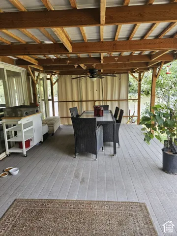 Covered outdoor covered deck featuring light wood-finish decking, exposed wood beams, and a corrugated metal ceiling