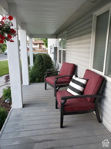 Covered front porch featuring a slatted floor and white support columns