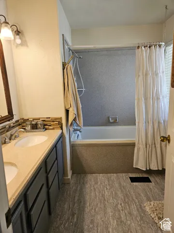 master bathroom featuring a dual sink vanity with a solid surface countertops. decorative tile backsplash, and dark cabinetry