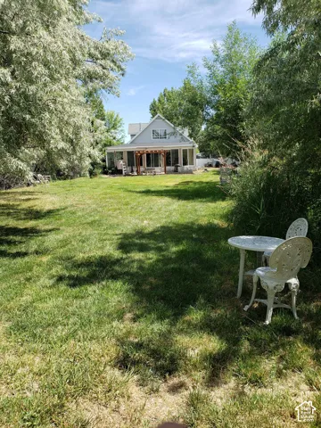 Spacious backyard featuring a manicured lawn, established trees, and a house with light-colored siding