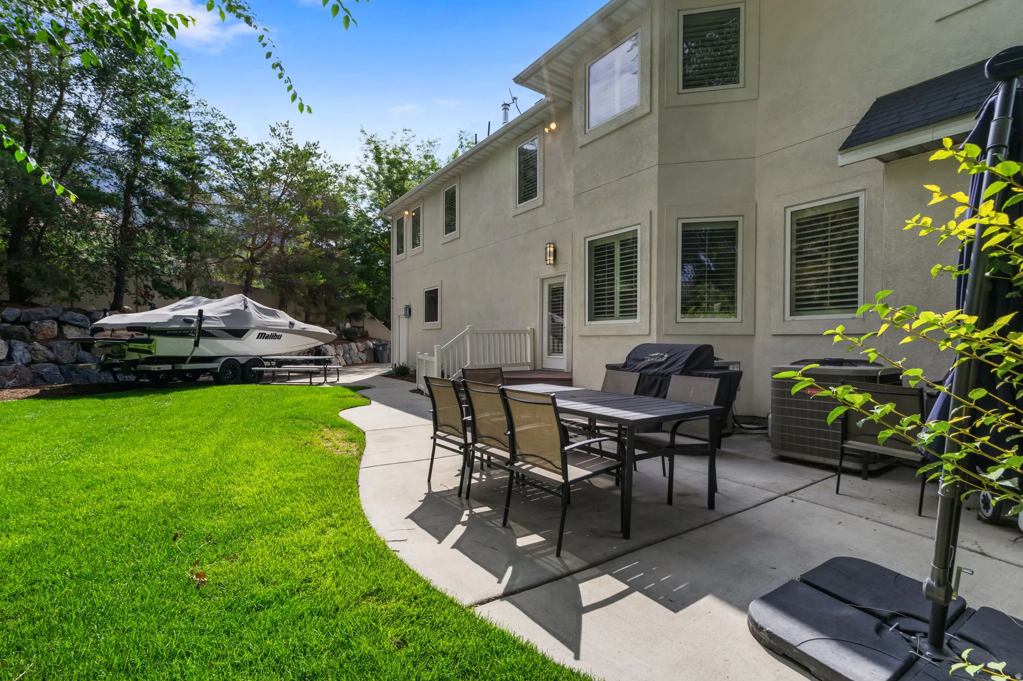 Expansive backyard featuring a manicured lawn, concrete patio, and stone retaining wall. RV Pad as well!